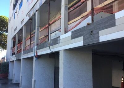 A multi-story building under construction with scaffolding and protective mesh.