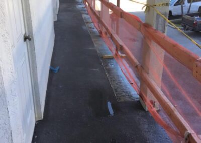 Corridor with orange construction netting on one side and doors on the other.